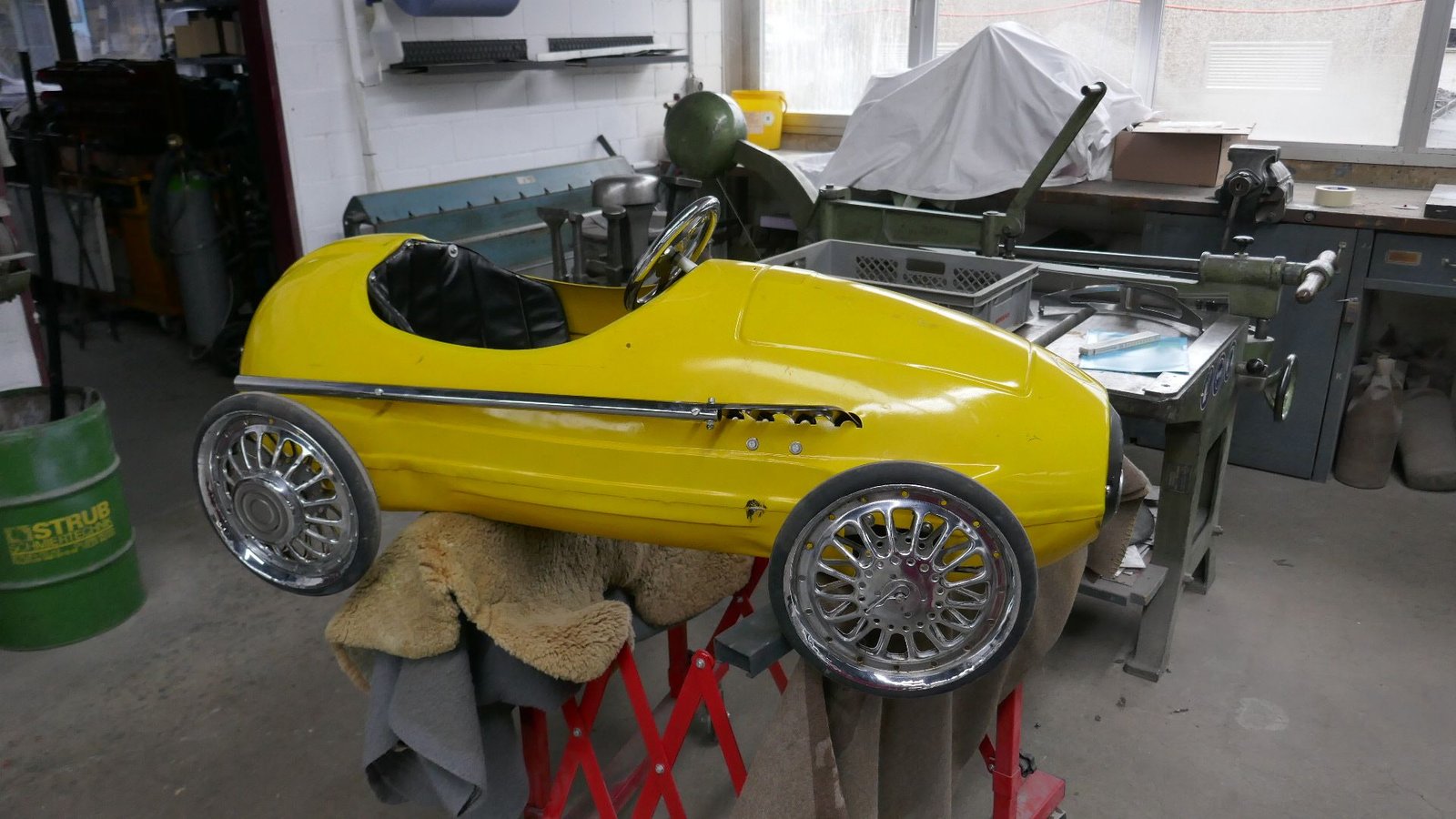 Ein gelbes Spielzeugauto steht auf einem Tisch in einer Garage.